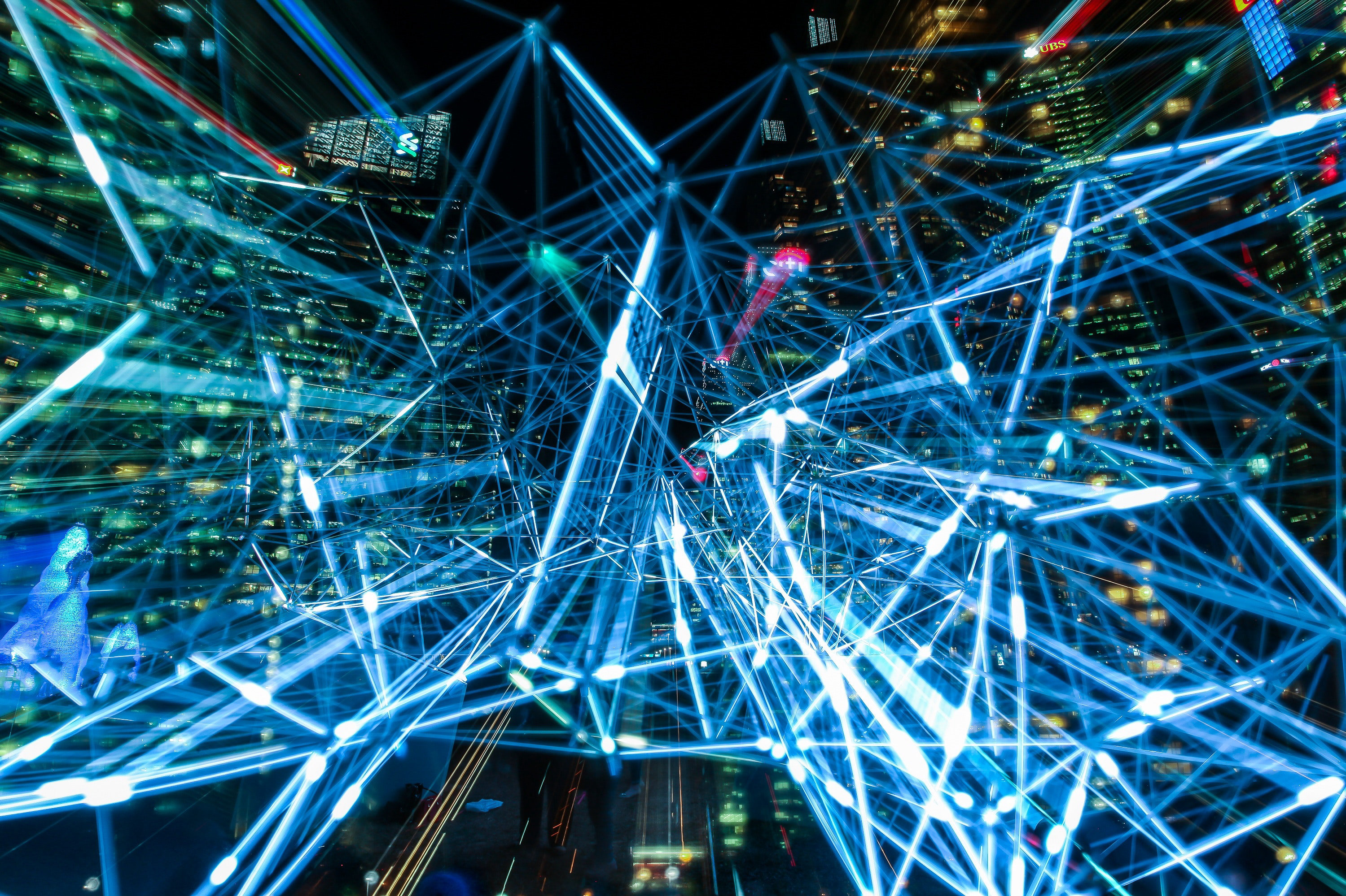 Abstract art of several bright blue lines with long-exposure and city lights in the background