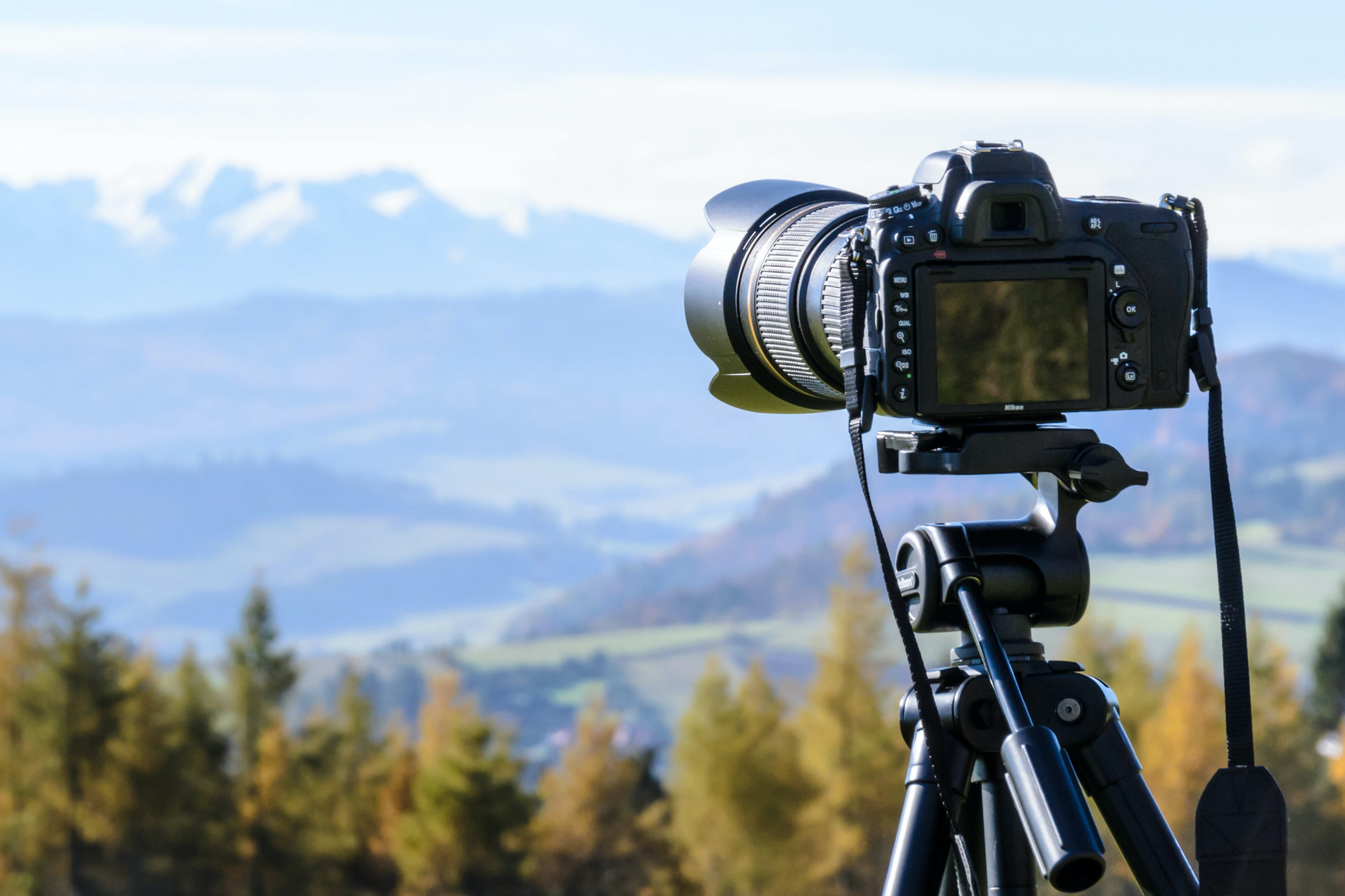 Camera on tripod, connected to laptop, ready to take pictures of food on table