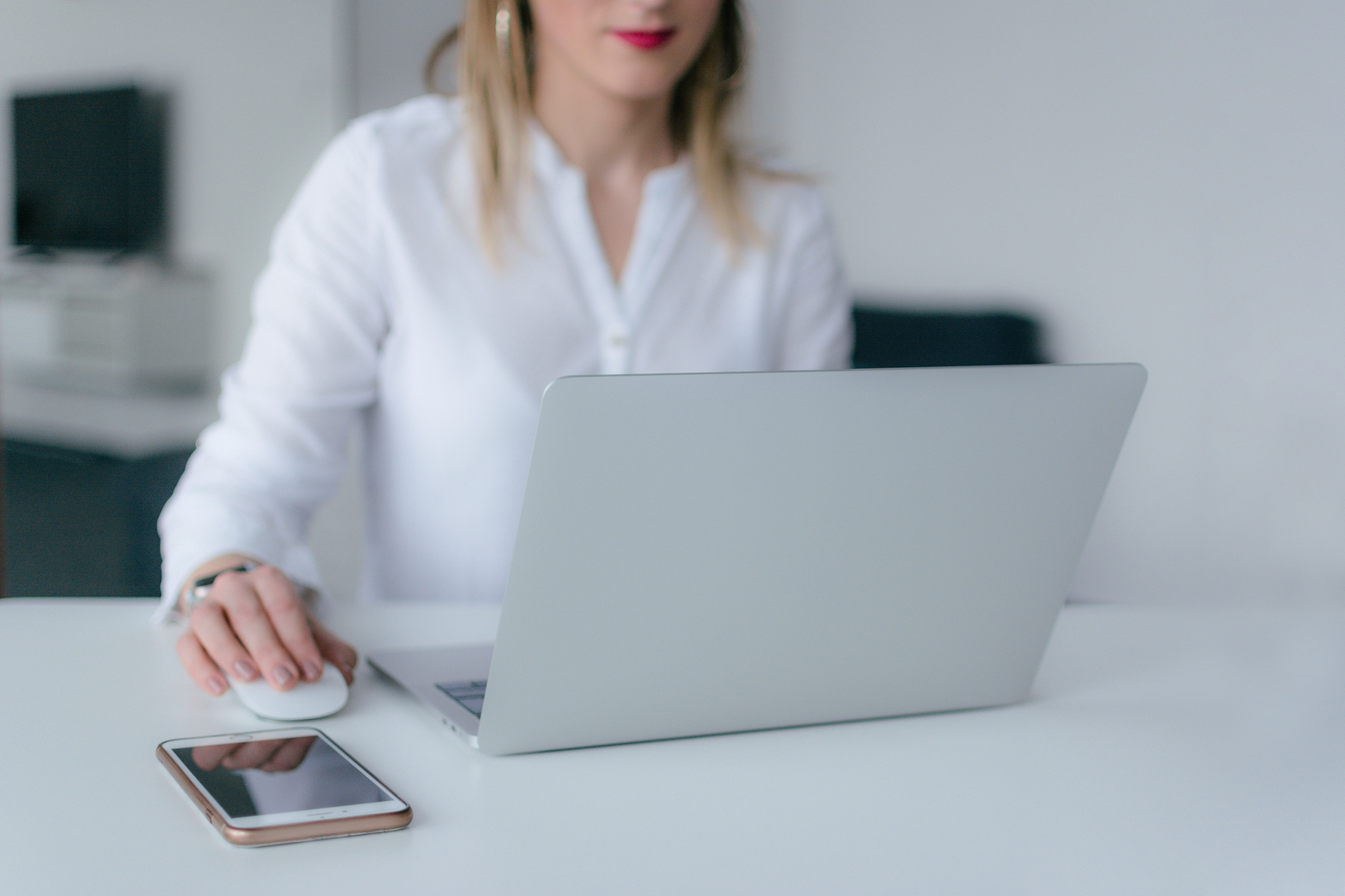 Woman using high-end designer computer on a bright desk with a large-screen phone